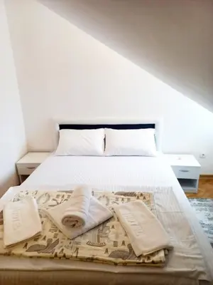 a bedroom with a bed with white sheets and pillows at A&A in Vrnjačka Banja