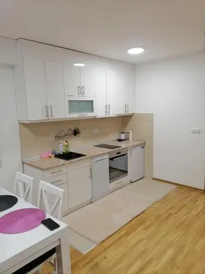 a kitchen with white cabinets and a table at APARTMANI CEPERKOVIC in Vrnjačka Banja
