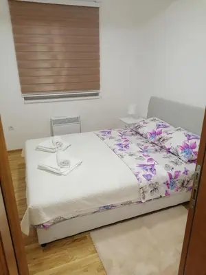 a bedroom with a white bed with flowers on it at APARTMANI CEPERKOVIC in Vrnjačka Banja