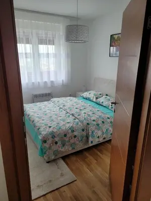 a bedroom with a bed with a blue comforter at APARTMANI CEPERKOVIC in Vrnjačka Banja