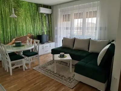 a living room with a green couch and a table at APARTMANI CEPERKOVIC in Vrnjačka Banja