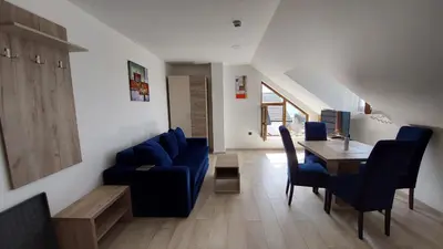 a living room with a blue couch and a table at Ctrl Alt Del Apartment S76 in Kopaonik
