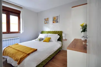 a bedroom with a bed with a green headboard at Apartman Antic 1 in Vrnjačka Banja