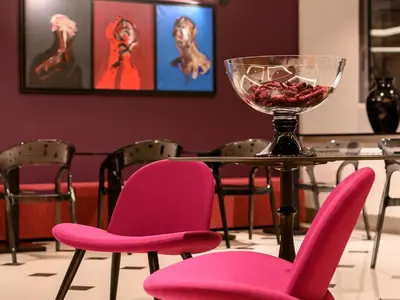 a table with pink chairs and a glass bowl of fruit at ArtLoft Garni Hotel in Niš