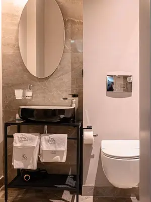 a bathroom with a sink and a toilet and a mirror at ArtLoft Garni Hotel in Niš