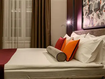 a bed with four pillows on top of it at ArtLoft Garni Hotel in Niš