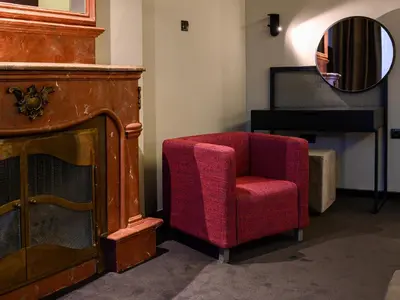 a red chair and a mirror in a room at ArtLoft Garni Hotel in Niš
