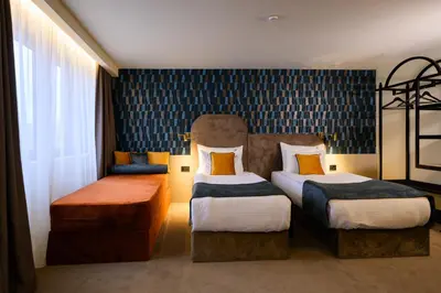 a hotel room with two beds and a chair at ArtLoft Garni Hotel in Niš