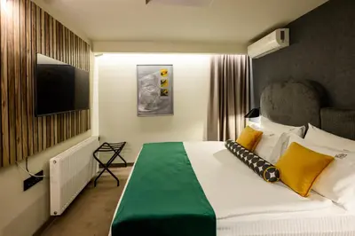 a bedroom with a bed with yellow and green pillows at ArtLoft Garni Hotel in Niš