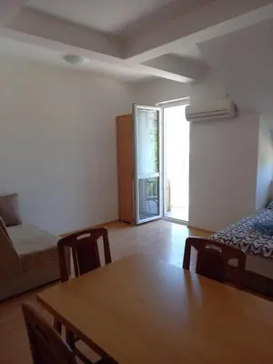 a living room with a table and a bed and a window at Smeštaj Voli - Borići studio-apartman, Sokobanja in Soko Banja