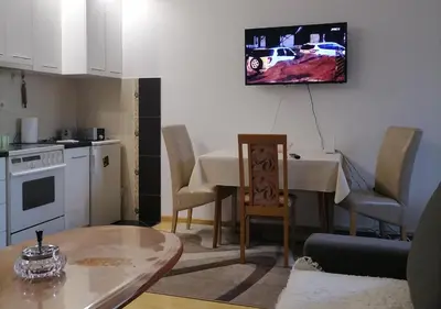 a living room with a table and a tv on the wall at Apartman Boki in Vrnjačka Banja
