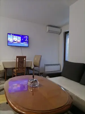 a living room with a table and a tv on the wall at Apartman Boki in Vrnjačka Banja