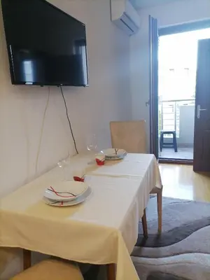 a table with two glasses and a television on the wall at Apartman Boki in Vrnjačka Banja
