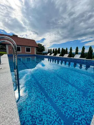 a large swimming pool with blue water at Djokić 2 sa bazenom in Soko Banja