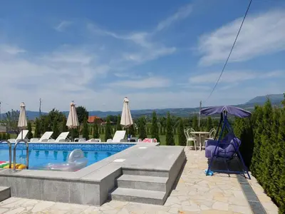 a swimming pool with an umbrella and some chairs and an umbrella at Djokić 2 sa bazenom in Soko Banja