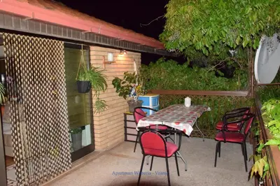 a table and chairs on a patio at night at Apartman Wisteria in Vranje