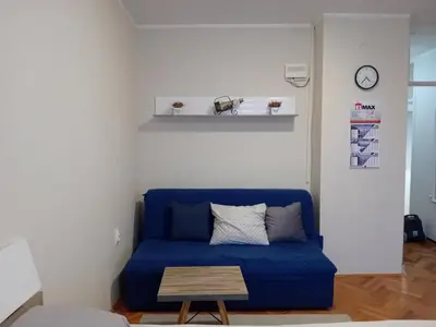 a blue couch in a living room with a table at Apartman A-1 in Zaječar