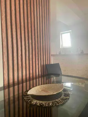 a room with a table and a chair and a curtain at City view & pool apartment in Niš