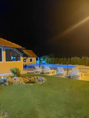 a group of chairs sitting in a yard at night at Djokić 3 sa bazenom in Soko Banja