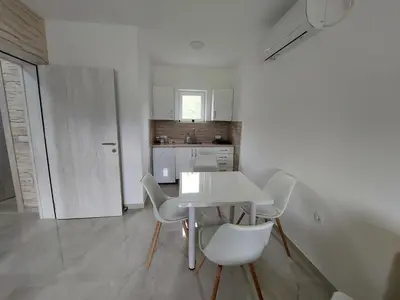 a white table and chairs in a white kitchen at Djokić 3 sa bazenom in Soko Banja