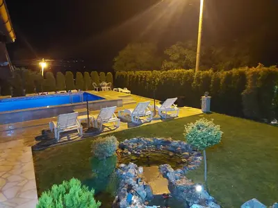 a yard with chairs and a swimming pool at night at Djokić 3 sa bazenom in Soko Banja