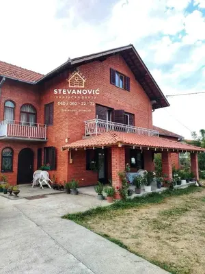 a red brick building with a cow in front of it at Stevanovic Smestaj in Vrnjci