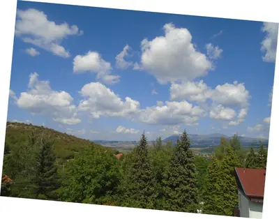a blue sky with clouds and trees on a hill at Apartman IKA Sokobanja in Soko Banja