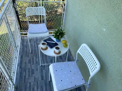 a balcony with two chairs and a table with a graduation hat at Apartman Jorgos in Soko Banja