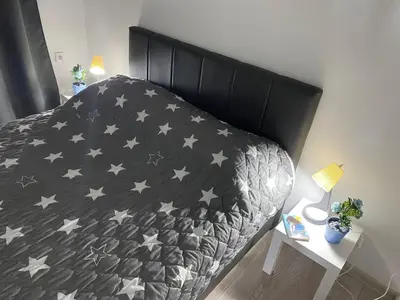 a bed with a black comforter with stars on it at Apartman Jorgos in Soko Banja