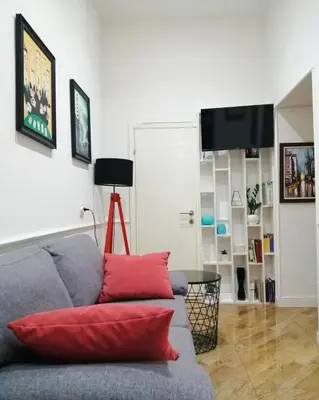 a living room with a gray couch with red pillows at Sleep Hostel in Niš
