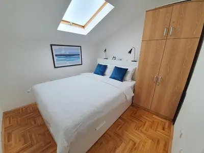 a bedroom with a large white bed with blue pillows at Le Soleil Apartman Vrnjačka Banja in Vrnjačka Banja