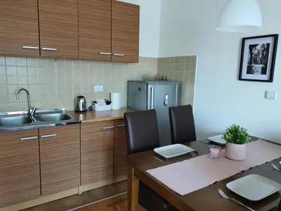 a small kitchen with a table and a refrigerator at Le Soleil Apartman Vrnjačka Banja in Vrnjačka Banja