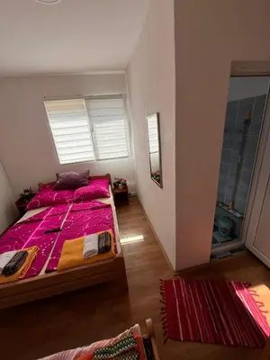 a bedroom with a bed with pink sheets and a window at Dedovina in Soko Banja