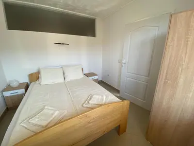 a bedroom with a bed with white sheets and a door at Apartmani Bambi Sokobanja in Soko Banja