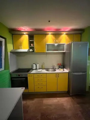 a kitchen with yellow cabinets and a stainless steel refrigerator at Greenspace in Niš