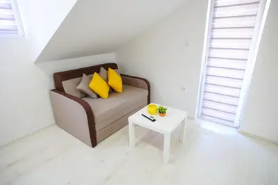 a living room with a couch with yellow pillows and a table at Apartmani Hedonist in Soko Banja