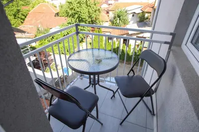 a balcony with a glass table and two chairs at Apartmani Hedonist in Soko Banja
