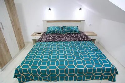a bedroom with a bed with blue and green bedspread at Apartmani Hedonist in Soko Banja