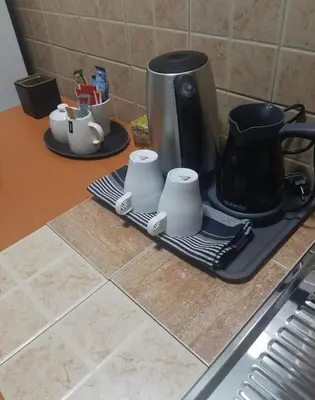 a counter with a coffee pot and cups on a drying rack at Apartman Ana in Leskovac