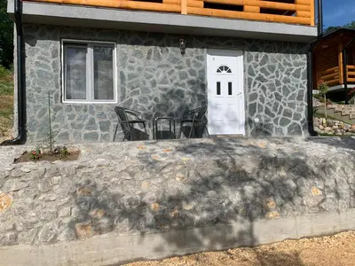 a stone house with a white door and chairs at Boja Zalaska - kameni apartman in Jagodina