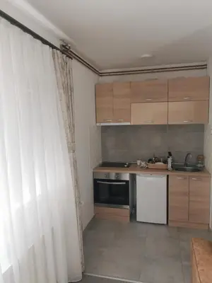 a kitchen with wooden cabinets and a white curtain at Restoran Mijajlovic in Kuršumlija