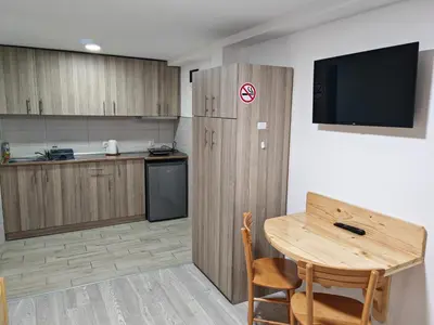 a kitchen with a table and a television and a table and chairs at Studio sa francuskim i pomoćnim ležajem - Romansa in Ribarska Banja