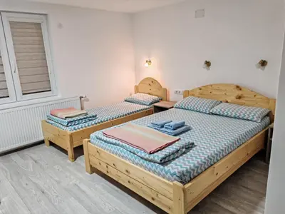 two twin beds in a room with a window at Studio sa francuskim i pomoćnim ležajem - Romansa in Ribarska Banja