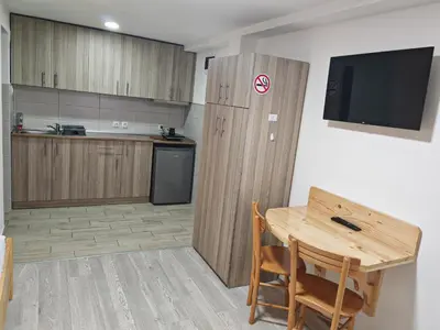 a kitchen with a table and a wooden partition with a television at Studio sa francuskim i pomoćnim ležajem - Romansa in Ribarska Banja