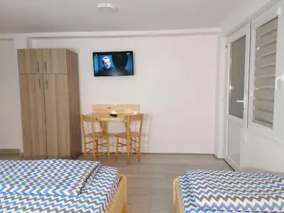 a room with two beds and a table with a tv on the wall at Studio sa francuskim i pomoćnim ležajem - Romansa in Ribarska Banja