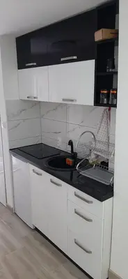 a kitchen with white cabinets and a black counter top at Adrijana 2 Apartmani in Vrnjačka Banja