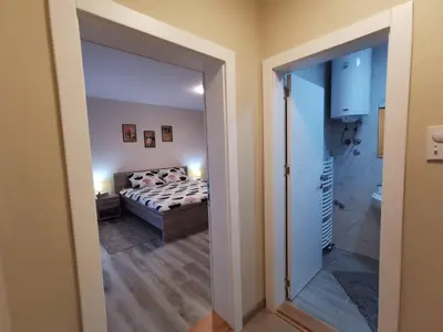 a bedroom with a bed and a door leading to a bathroom at Apartmani MALINA in Vrnjačka Banja