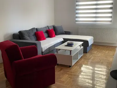 a living room with a couch and a red chair at City Apartmani Niš in Niš