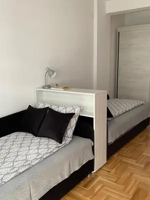 a room with two beds and a desk with a bed sidx sidx sidx at City Apartmani Niš in Niš