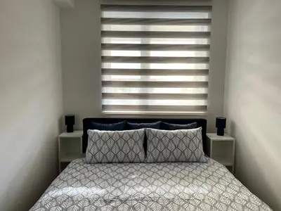 a bedroom with a bed and a large window at City Apartmani Niš in Niš